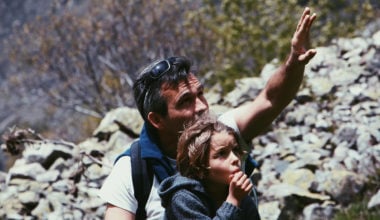 father hiking with son pointing upwards