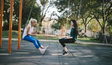 two girls sitting on swings facing each other