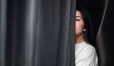 girl hiding behind curtain